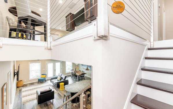 Un interior de varios niveles con una escalera, un comedor y una sala de estar.