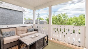A covered balcony with a beige sofa, a glass coffee table, and a laptop. - Highlands Lookout-3BR 3.5BA-Walk to Tons +Parking (Louisville)