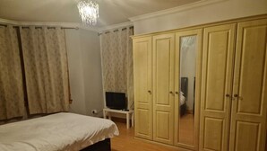Un dormitorio con una cama, un televisor sobre una mesita y un armario.