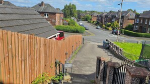 Una calle residencial con casas, una valla de madera y un camino pavimentado.