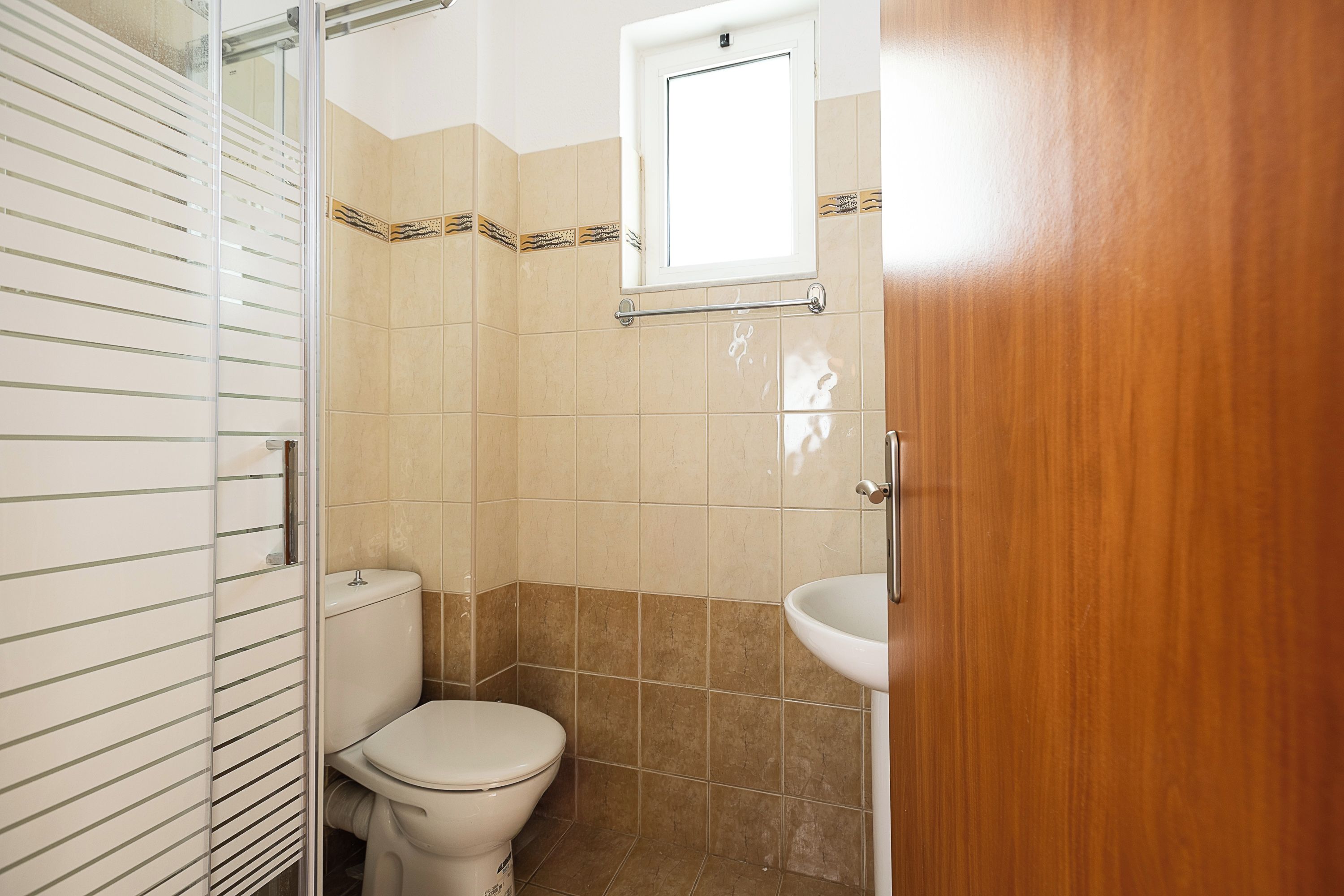 Een badkamer met toilet, wastafel en raam.