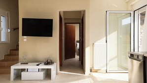A modern living room with a flat-screen TV, a white console table, and a sliding glass door leading to a balcony. - Seaview Villa Marije, By Idealstay Experience (9QRP+JJM Geropotamos, Greece)