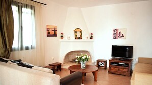 Ein Wohnzimmer mit einer Couch, einem Couchtisch, einem Kamin, einem Fernseher und Kunstwerken an den Wänden.