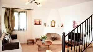 Ein Wohnzimmer mit einer Couch, einem runden Couchtisch, einem Kamin und einer Treppe.