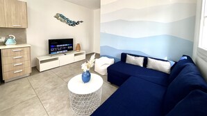 A modern living room with a sofa, TV, and decorative wall art. - 33 AN - Stay Napa Ocean Apartment (Ayia Napa)