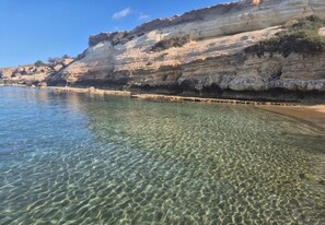 A clear coastal beach with visible stratified rock formations and calm water. - 85 KAP - Stay Mythical Blue Apartment (Paralimni)