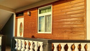 Une façade en bois agrémentée d’une fenêtre et d’une balustrade blanche décorative.