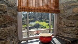 A stone wall, a window with a view of a garden, and a red pot on the sill. - Bluebell Cottage, Aberporth (Aberporth)