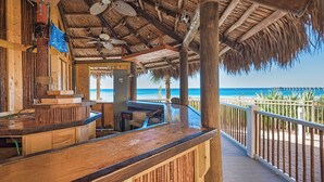 Een houten barruimte met rieten dak, met uitzicht op een strand.