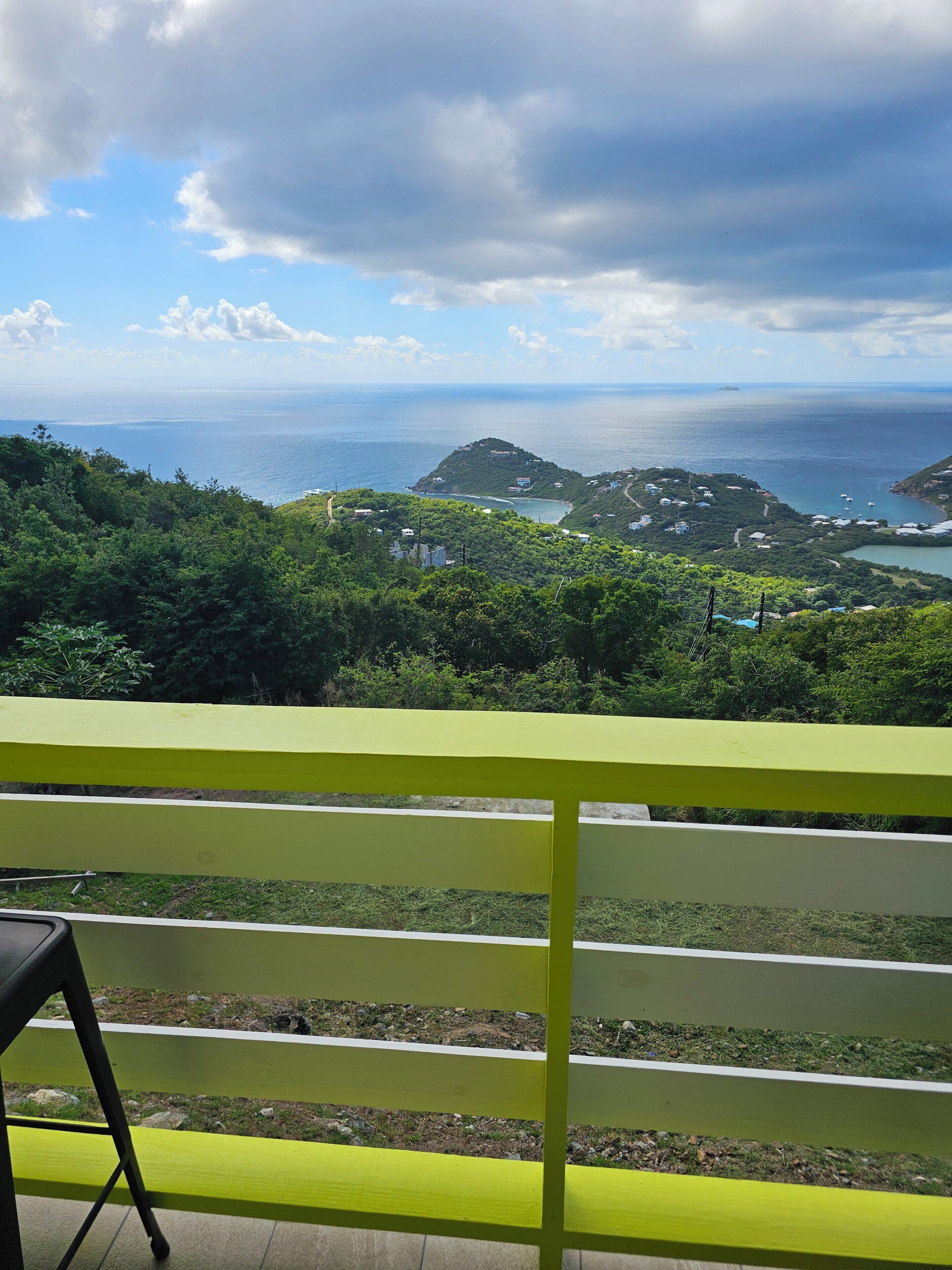 Un balcón con vistas a un paisaje costero, que incluye una pequeña isla y el mar.