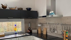 A modern kitchen with white cabinets, a black countertop, and a wooden ceiling. - Vacation home Annemie - very cozy and modern house with a beautiful garden (Markt Erlbach)