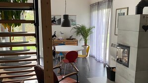 A modern kitchen with a built-in oven, a dining area with a round table and chairs, and a large window with plants. - Vacation home Annemie - very cozy and modern house with a beautiful garden (Markt Erlbach)