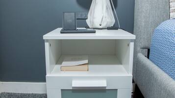 A white nightstand with a lamp, a book, and a small electronic device.