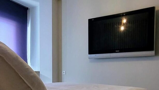 Une chambre avec deux lits, un téléviseur à écran plat fixé au mur et un luminaire au plafond.