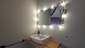 Une salle de bain avec un lavabo blanc, un plan de toilette en bois et un miroir avec éclairage intégré.