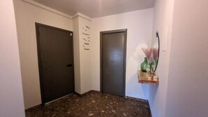 Un couloir avec deux portes, un mur orné d’une citation inspirante et une étagère avec des objets décoratifs.