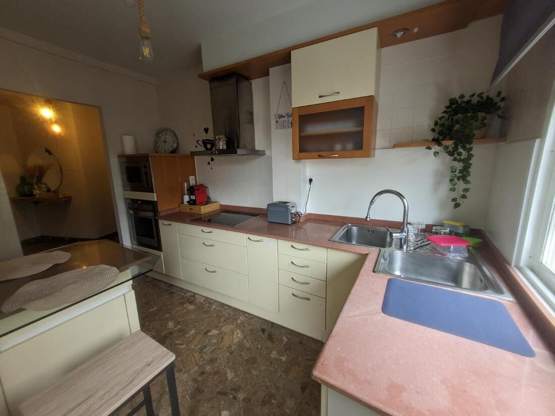 A kitchen with a sink, countertop, cabinets, and a window.