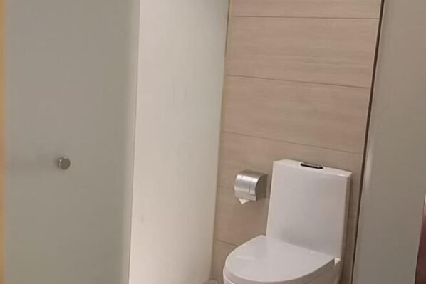 A bathroom with a toilet, a hand dryer, and a wall-mounted paper towel dispenser. - Vienna Zhihao Hotel (Guangzhou East Station Tianhe Bus Station Subway Station Store) (Guangzhou)