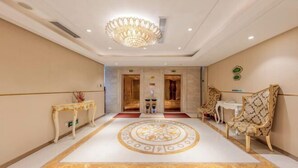 Un vestíbulo espacioso con un llamativo diseño en el suelo, elegantes lámparas de araña y muebles clásicos.