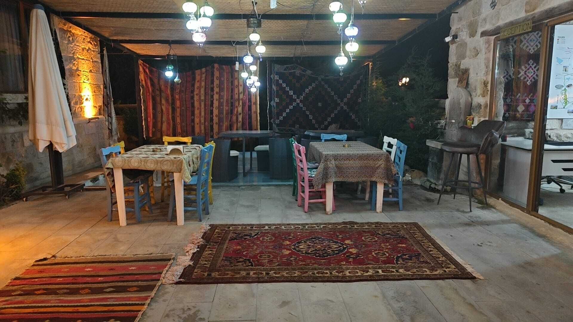 Een gezellig eetgedeelte met houten tafels en stoelen, een kamerbreed tapijt met dessin en een receptiebalie.