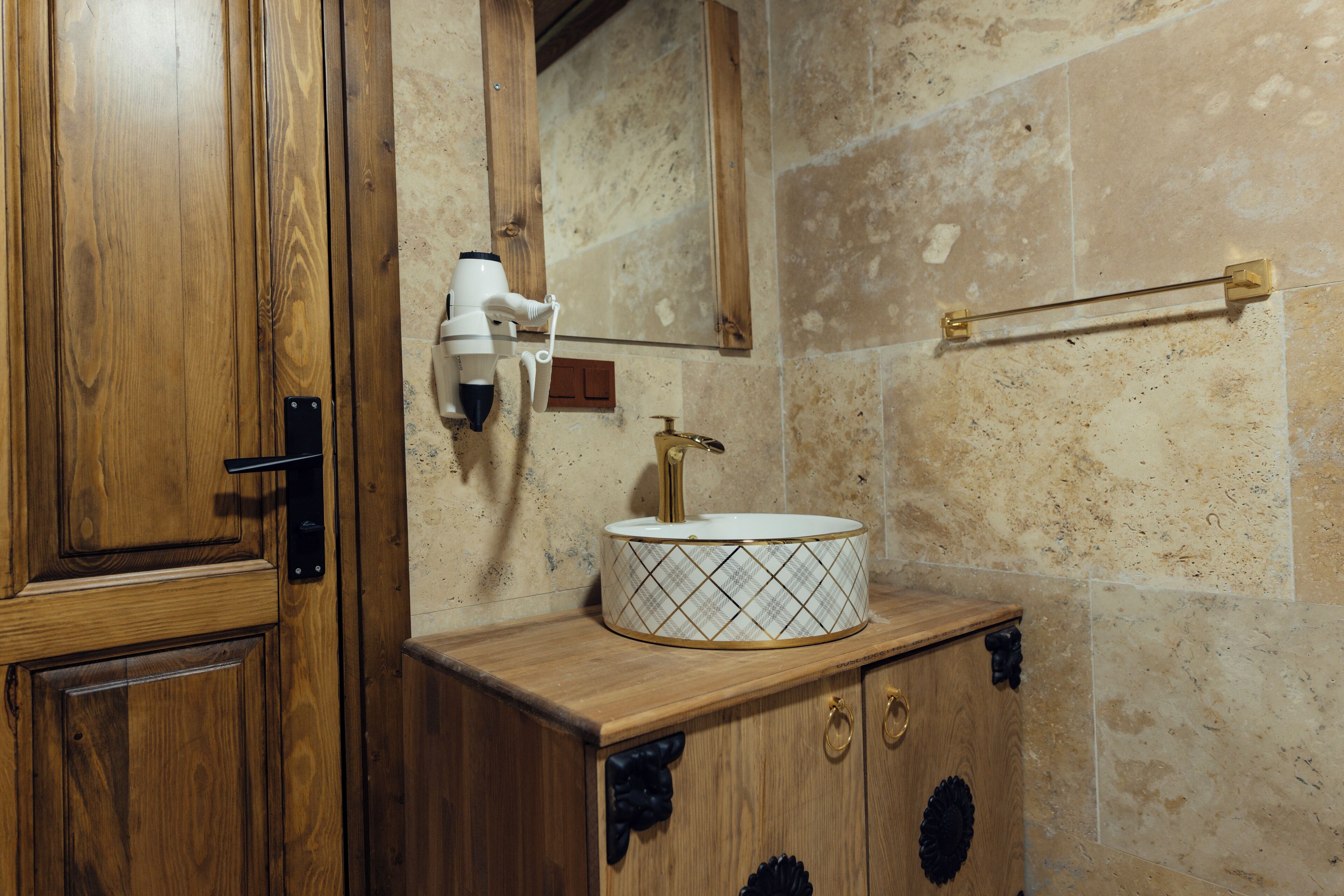 A wooden vanity with a white sink, a hairdryer, and a towel rack.