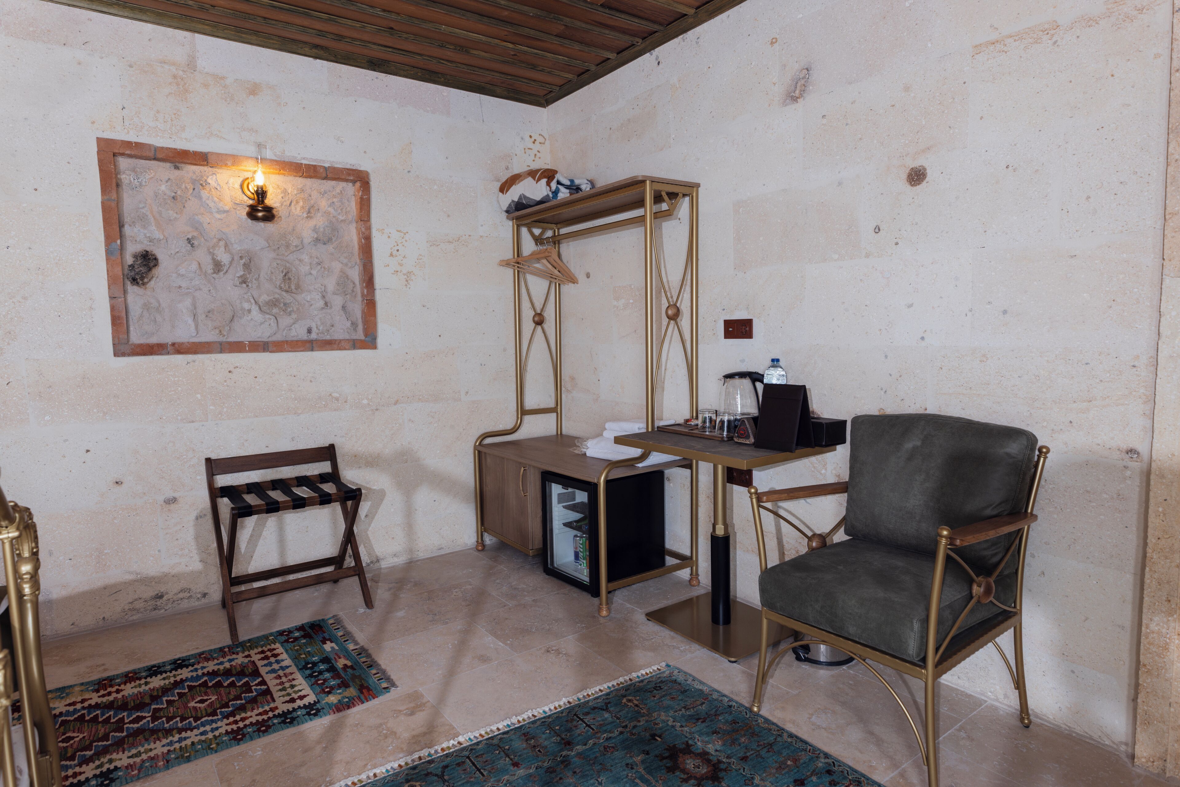 Um quarto com uma cadeira de madeira, uma mesa pequena com abajur e um tapete.