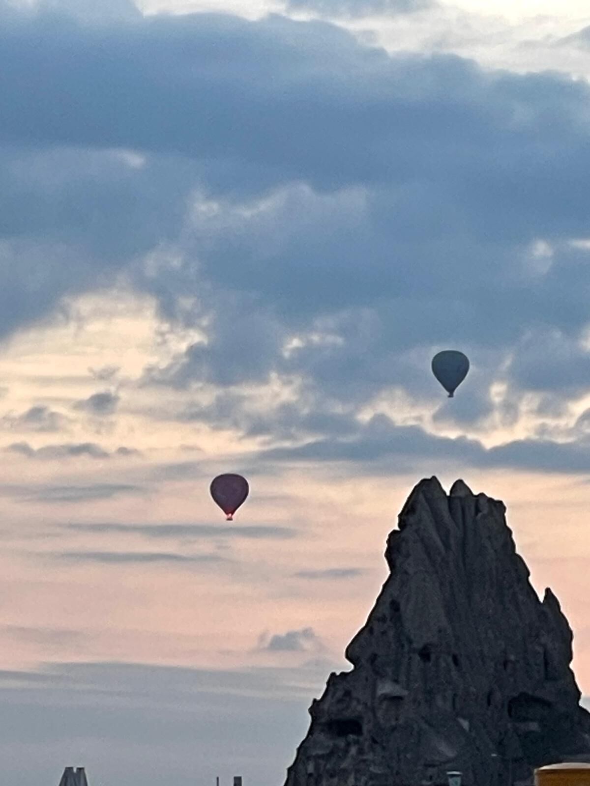 A rock formation with two hot air balloons in the sky.