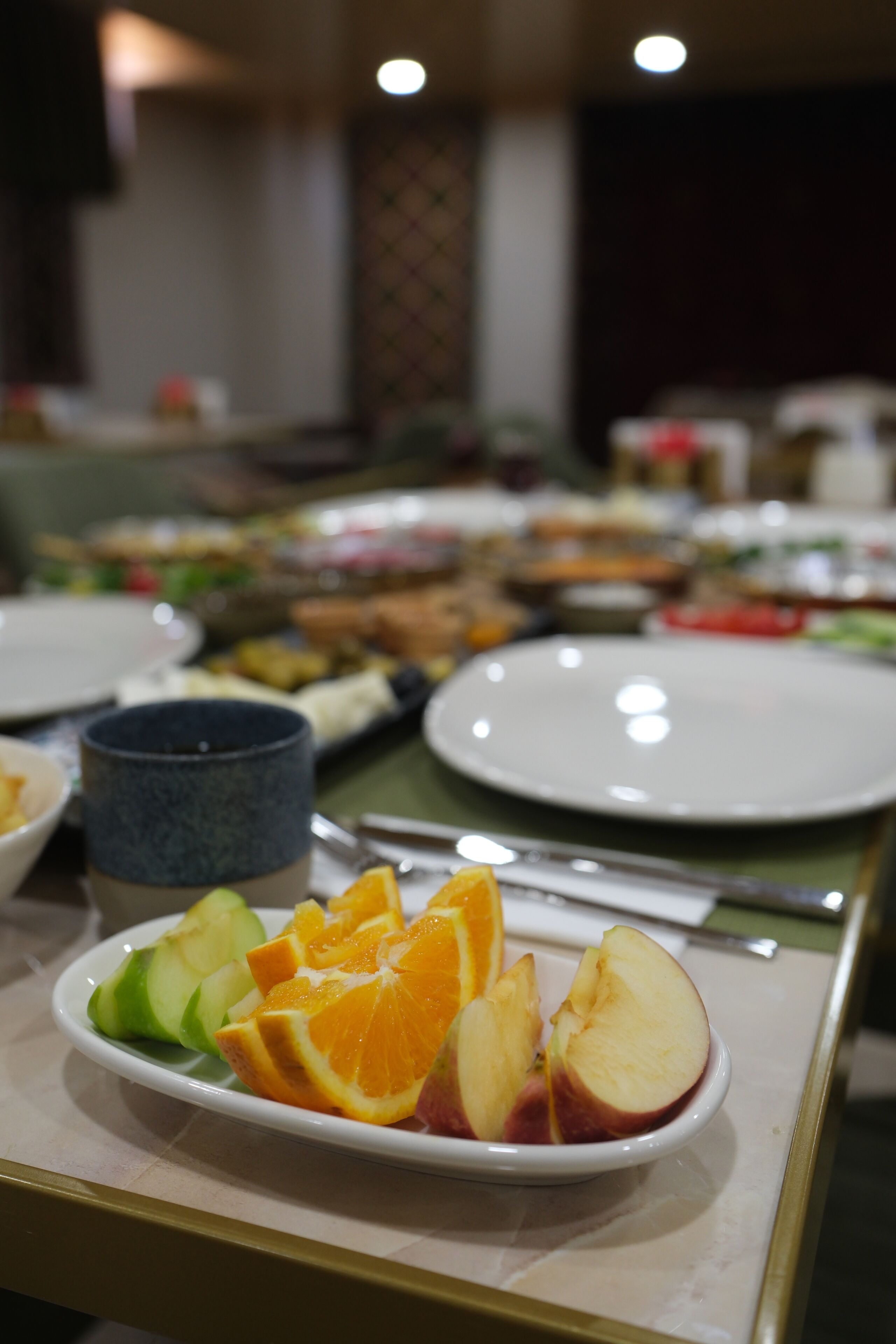 A buffet table with a plate of fruit in the foreground.