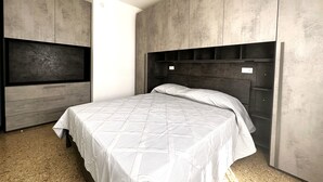 A bedroom with a bed, built-in TV, and a wardrobe. - Three-room apartment 350 m. from the sea in Bibione Pineda. (Bibione Pineda)