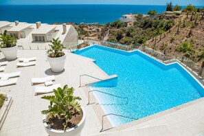 A swimming pool with a clear view of the ocean, surrounded by lounge chairs and potted plants. - Apartment Sleeps 4 With Gym & Spa (Benalmádena)