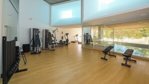 A spacious gym with various exercise equipment, large windows, and a view of greenery. - Apartment Sleeps 4 With Gym & Spa (Benalmádena)