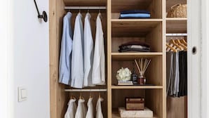 A wooden wardrobe with multiple shelves, some holding folded clothes, a small box, and a decorative item.
