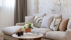 A living room with a beige sofa, a round coffee table, and a vase with flowers.
