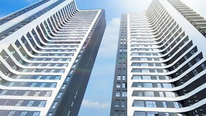 Two high-rise buildings with a modern architectural design, featuring curved balconies and a uniform window pattern.