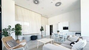 A modern living room with a sofa, a dining table, and a kitchen area in the background. - Modern Apartment With Views Urban Sky 26ke (Málaga)
