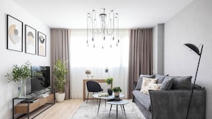 A modern living room with a sofa, TV, coffee table, and plants. - Modern Apartment With Views Urban Sky 26ke (Málaga)