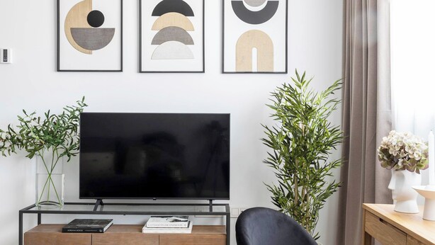 Un salon moderne doté d’un téléviseur à écran plat, d’un fauteuil en cuir noir et d’une décoration minimaliste.