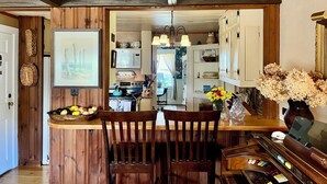 A wooden kitchen with a dining area, featuring a wooden ceiling, a microwave, and a stove.