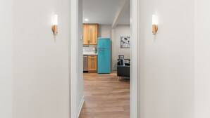 Un pasillo estrecho que lleva a una cocina con armarios de madera y un refrigerador color verde azulado.