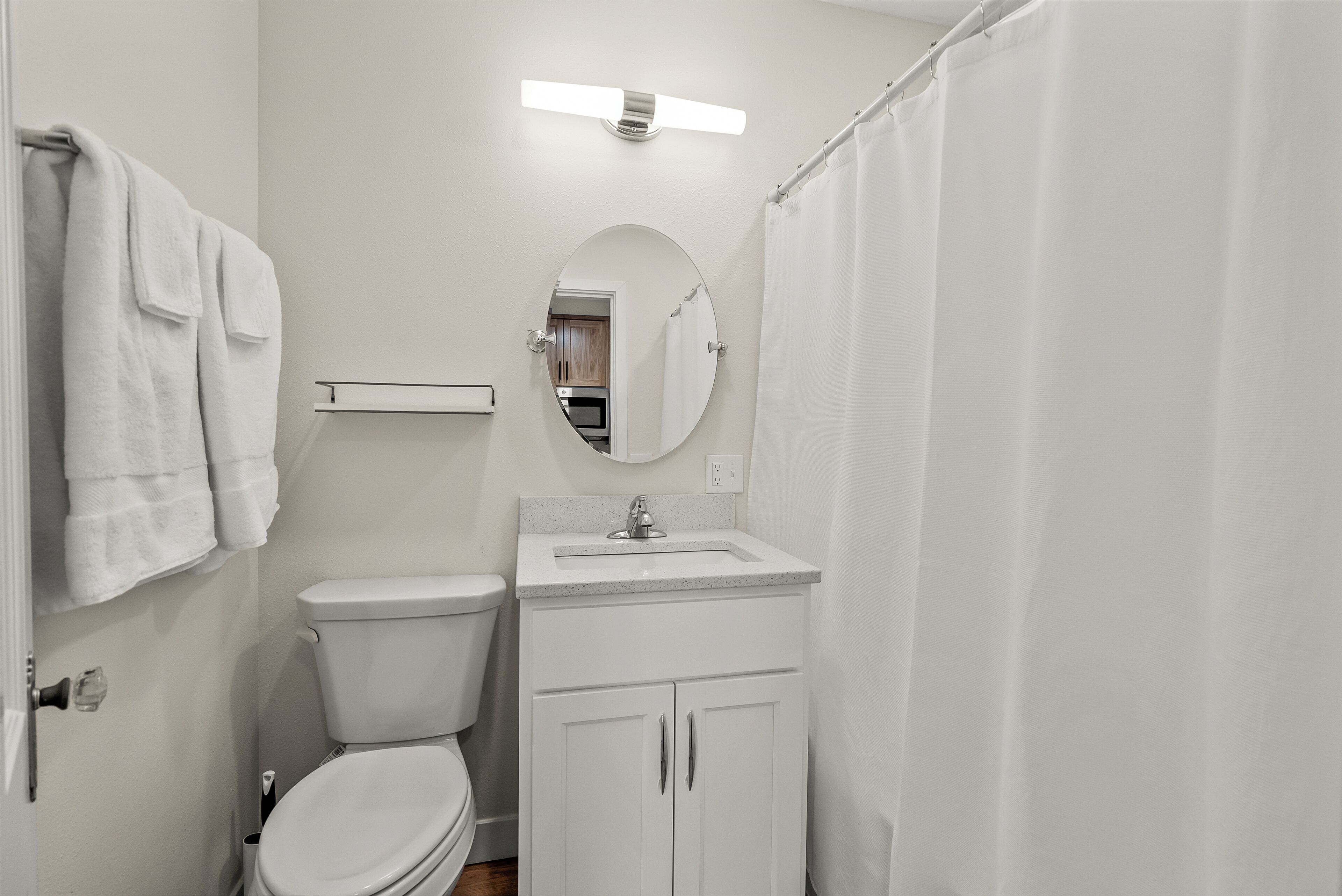 A bathroom with a toilet, sink, mirror, and shower curtain.