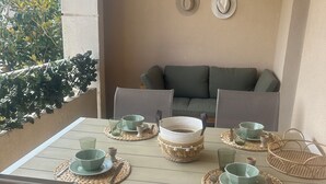 A dining area with a table set for four, surrounded by chairs, and a sofa in the background.