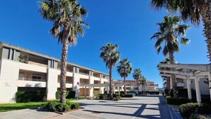 A hotel with a modern design, featuring a central courtyard with palm trees and a clear blue sky.