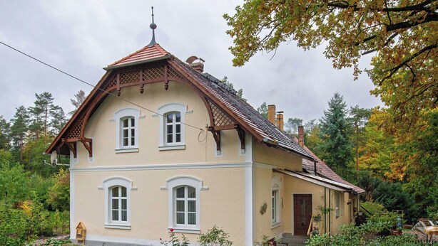 A two-story house with a sloped roof, multiple windows, and a chimney.
