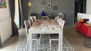 Un comedor con una mesa grande, sillas, un tapete estampado y adornos en la pared.