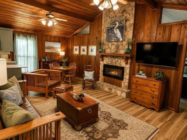 A cozy living room with a fireplace, wooden furniture, and a television.