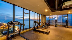 A gym with exercise equipment and large windows offering a view of a cityscape and mountains.