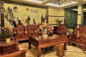 A traditional room with wooden furniture, a large painting, and a vase of flowers. - Jiajie Hotel (Xuanwei)