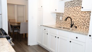 A kitchen with white cabinets, a granite countertop, and a patterned backsplash. - Spacious Condo in Southfield, Michigan (Southfield)