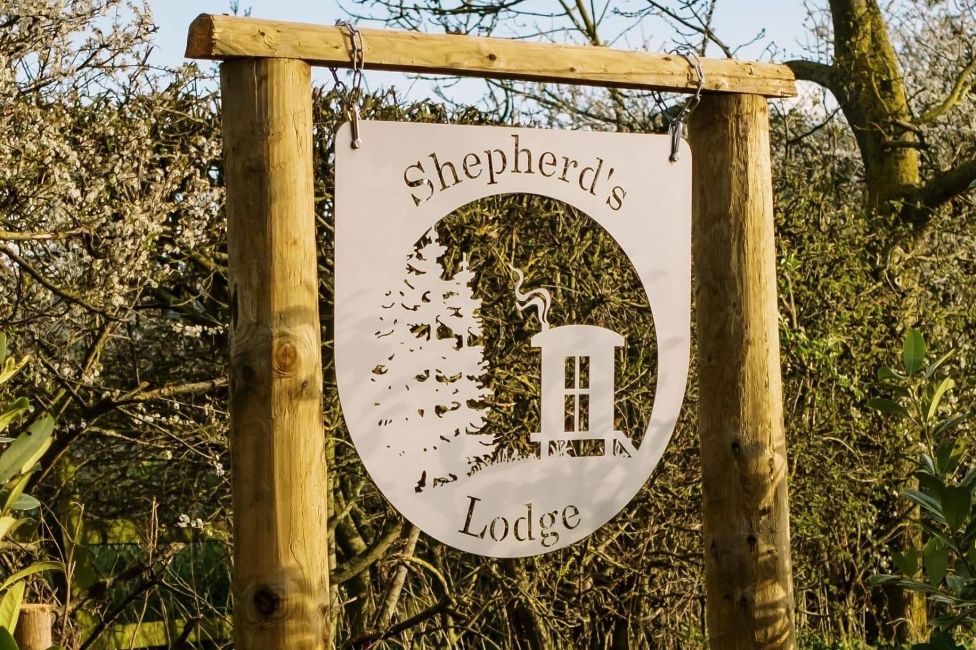 Un panneau en bois portant l’inscription « Shepherd’s Lodge » et représentant la silhouette d’une maison.