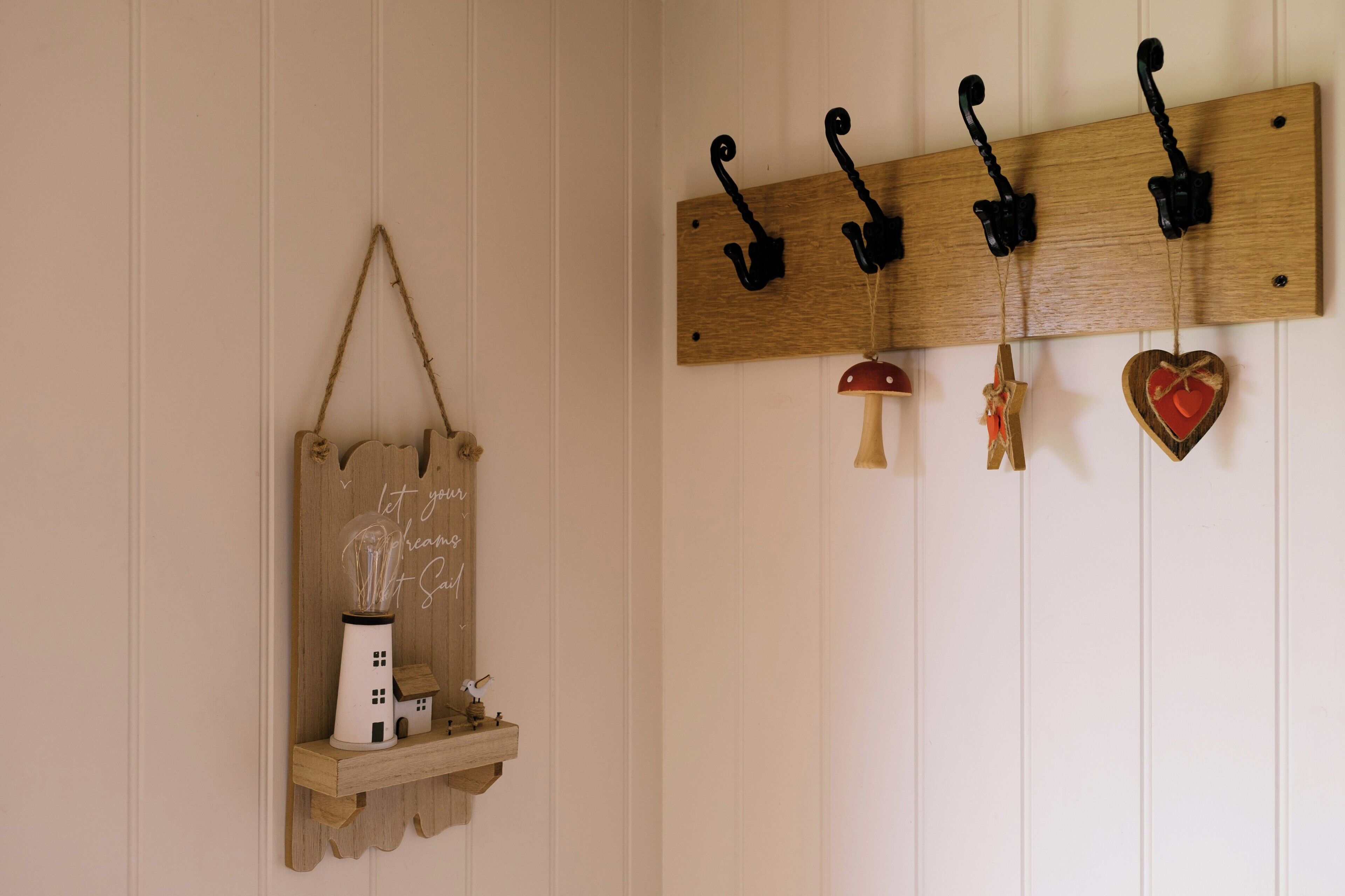 A wooden wall-mounted coat rack with hooks and a small shelf holding a decorative item.